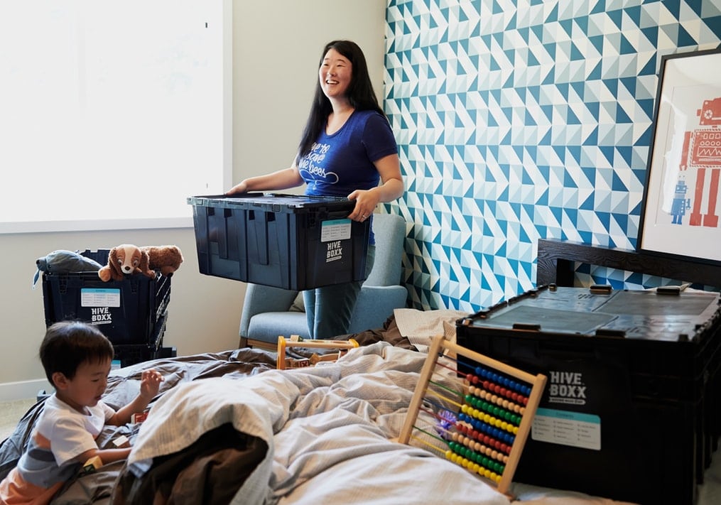 woman packing house while toddler plays 