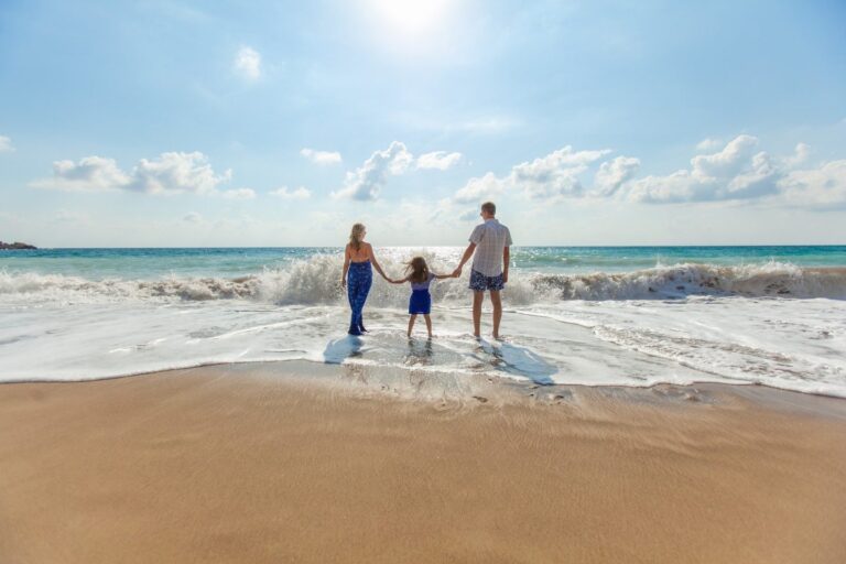 family on sandy beach standing in waves